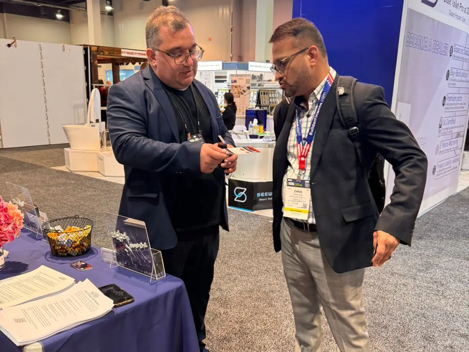 A CabinetBoost team member walking a KBIS 2025 attendee through the program at the booth table